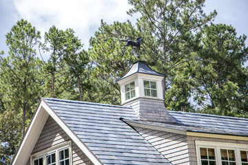 weathervane on top of house with shingle roof and gray walls - obrazy, fototapety, plakaty