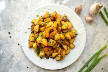 Chips with chives. Fried Potatoes with green beans, asparagus. Food in a  plate on a dark black concrete table background.