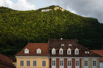 Fototapeta na wymiar Brasov sign on the hill and city architecture