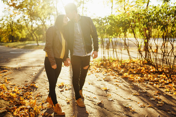 Obraz premium Lovely beautiful couple enjoying each other. Beautiful autumn day. Lifestyle, happy couple of two play on a sunny day in the park. The concept of youth, love and lifestyle.