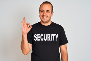 Young safeguard man wearing security uniform standing over isolated white background doing ok sign...