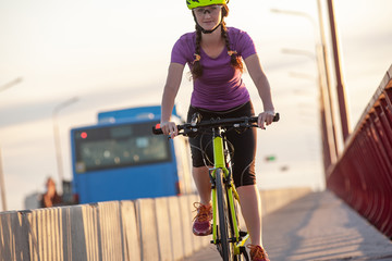 Attractive girl looking into camera while riding bicycle on road