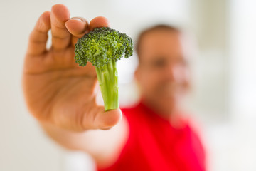 Fototapeta na wymiar MIiddle age man showing piece of broccoli