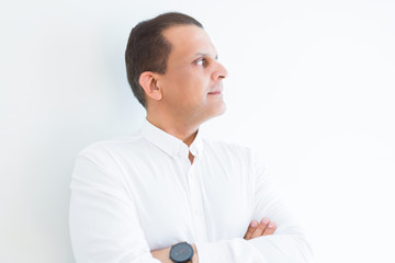 Naklejka premium Middle age business man looking natural and relaxed with crossed arms over white wall background