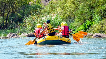 Rafting trip. A group of men and women descends on a large inflatable boat on the river.