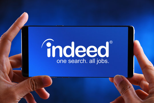 Hands holding smartphone displaying logo of Indeed