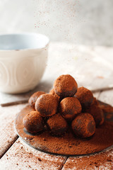 Cocoa balls, chocolate truffle cakes on a black slate tray, sprinkled with cocoa powder. Process of cooking