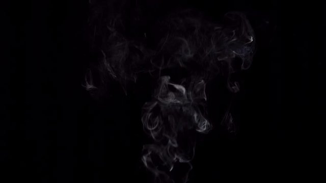 White smoke billows on a black background, a place for text.