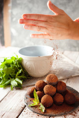 Cocoa balls, chocolate truffle cakes on a black slate tray, sprinkled with cocoa powder. Process of cooking