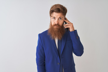 Young redhead irish businessman talking on the smartphone over isolated white background with a confident expression on smart face thinking serious