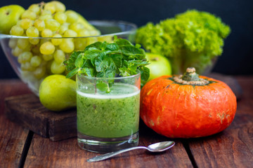 Diet drink, smoothie. Green color. Body cleansing. Diet. Nearby are orange pumpkin, pears, apple, mint leaves, pepper. Lobules of Lemon. A bunch of white grapes. Healthy eating Light breakfast. 