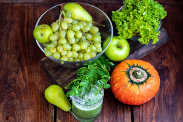 Diet drink, smoothie. Green color. Body cleansing. Diet. Nearby are orange pumpkin, pears, apple, mint leaves, pepper. Lobules of Lemon. A bunch of white grapes. Healthy eating Light breakfast. 