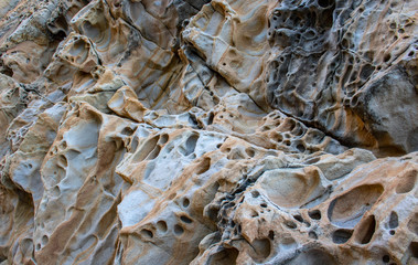 Texture, background layers and cracks in sedimentary rock on cliff face. Cliff of rock mountain. Rock slate in the mountain. Seamless abstract background. Cracks and layers of sandstone