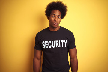 American safeguard man with afro hair wearing security uniform over isolated yellow background...