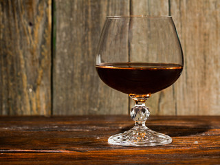 glass with cognac close-up on an old wooden background