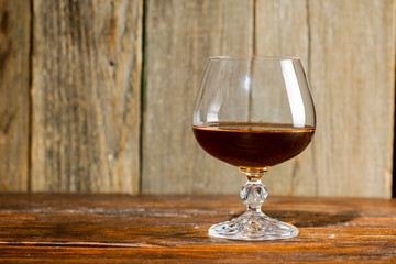 glass with cognac close-up on an old wooden background