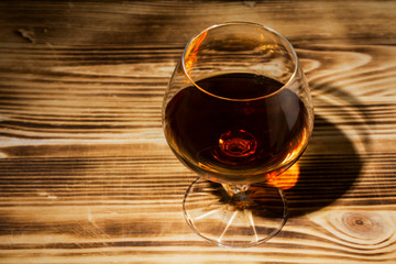 glass with cognac close-up on an old wooden background
