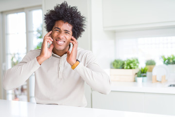 African American man at home covering ears with fingers with annoyed expression for the noise of loud music. Deaf concept.