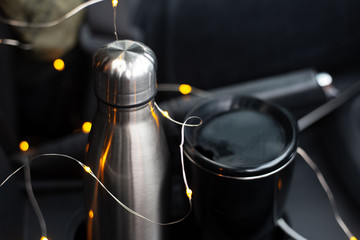 Steel thermo bottle and black mug for coffee in car
