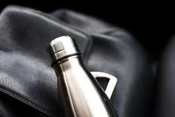 Close-up of steel thermo bottle on black backpack