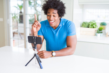 African American man doing online call with webcam using smartphone surprised with an idea or question pointing finger with happy face, number one