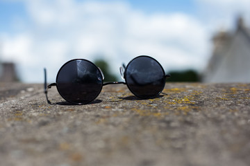 Close-up of black round sunglasses on stone