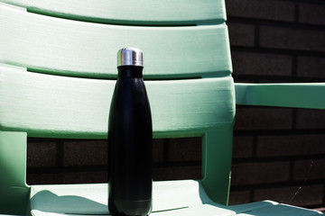 Black thermo bottle on green chair