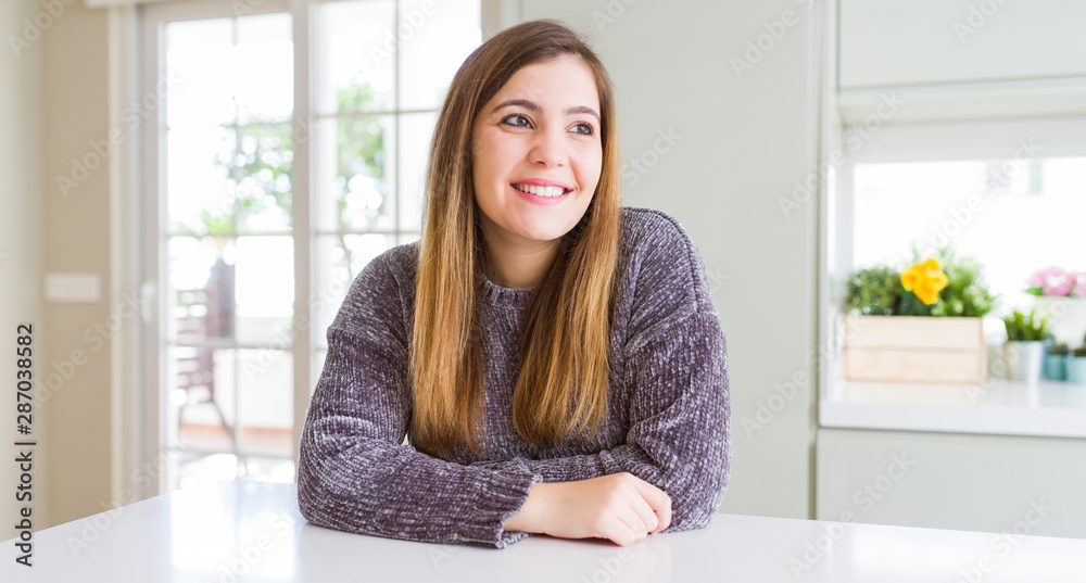 Sticker Beautiful young woman at home looking away to side with smile on face, natural expression. Laughing confident.