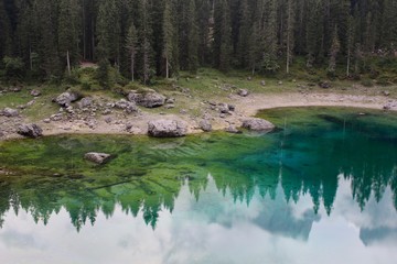 Lake Carezza, mountain lake famous. Reflection of the Rose Garden Mountain in the Lake. In 2018, a massive storm destroyed all the trees in the area. South Tirol, Italy 