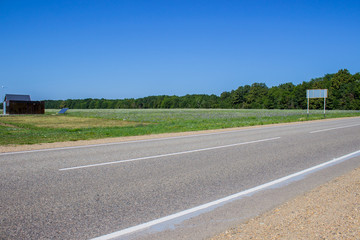 Road in a rural area with trees and blue sky