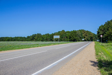 Road in a rural area with trees and blue sky