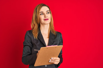 Fototapeta premium Young beautiful redhead businesswoman wearing suit writing on flip board