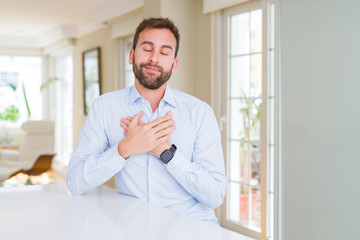Naklejka na ściany i meble Handsome business man smiling with hands on chest with closed eyes and grateful gesture on face. Health concept.
