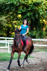 Young beautiful brunette girl riding on a horse.