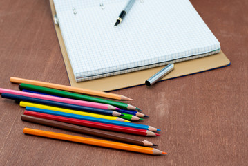 Blank paper and colorful pencils on old wooden table. Flat lay, top view.