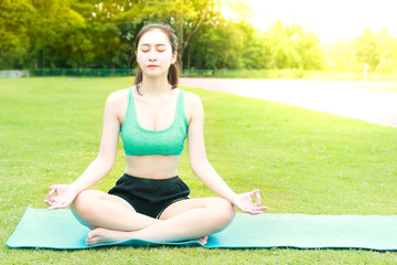 Pretty Asian teen girl is practicing yoga in the garden park at nature, sport female is doing exercise outdoor, fitness and healthy lifestyle concept.