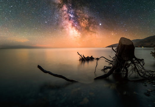 Old stump in the lake and beautiful milky way galaxy. Long exposure. Sevan lake Armenia.