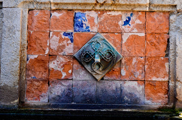 Detail of an arabic water fountain with red bricks and copper tap