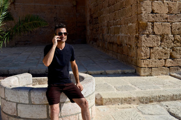Fototapeta na wymiar Man wearing black t-shirt and sunglasses talking with his cell phone