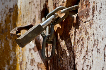 Detail of  old padlock with chain closing and old wooden door