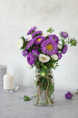 beautiful bouquet of purple and white flowers in a glass vase on a light background
