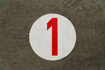 Red number one inside white circle painted on concrete background