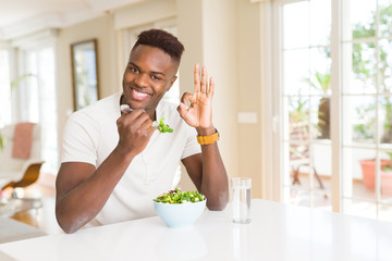 African american man eating fresh healthy salad doing ok sign with fingers, excellent symbol