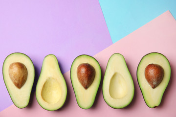 Cut fresh ripe avocados on color background, flat lay with space for text