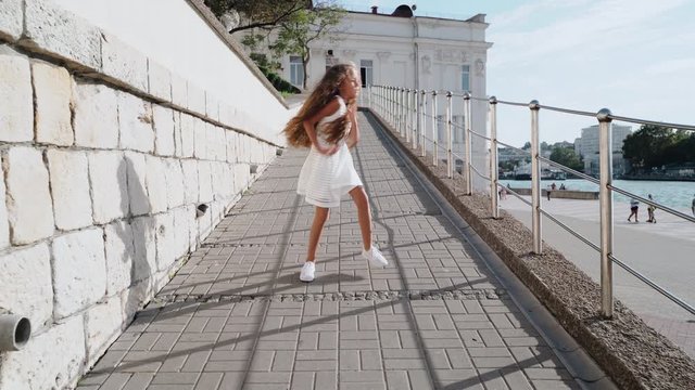 Kid girl dancing on the street at summer