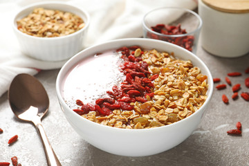 Smoothie bowl with goji berries and spoon on beige marble table