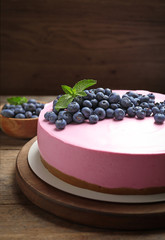 Board with tasty blueberry cake on wooden table. Space for text