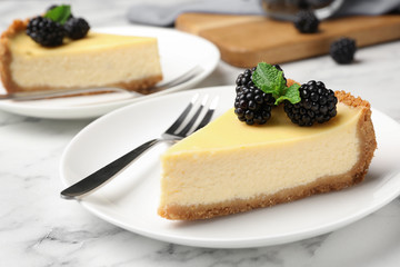 Piece of delicious cheesecake decorated with blackberries on table
