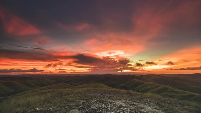 Picturesque vast Wairinding Hills against sunset in boundless orange sky with grey clouds on horizon time lapse. Concept beautiful nature landscape of tropical Sumba island, Indonesia. 4K shot
