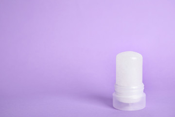 Natural crystal alum stick deodorant on lilac background. Space for text